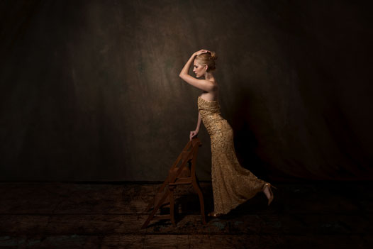 Portrait einer Frau im Abenkleid an einer Leiter gelehnt